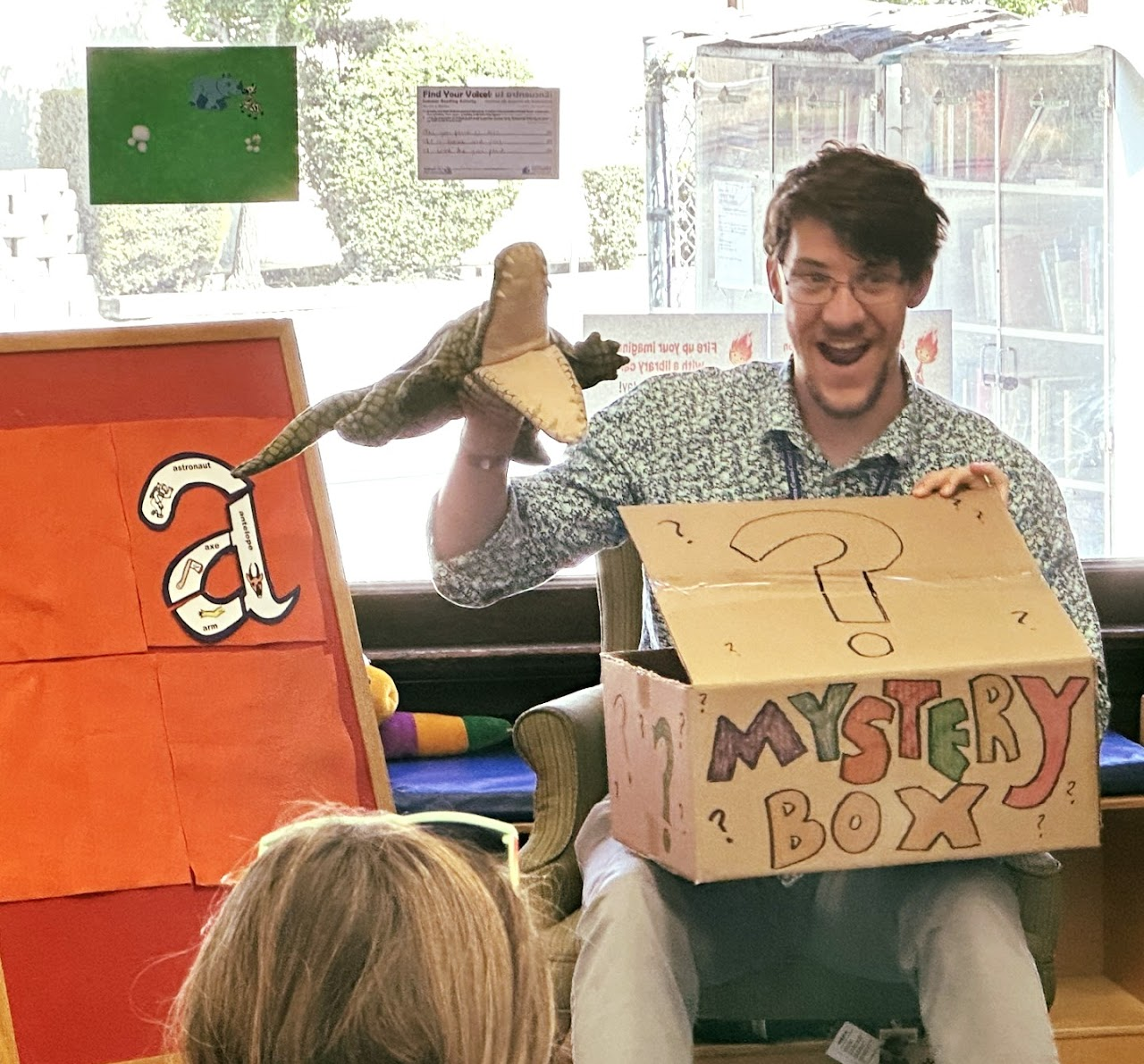 Mark performing a library storytime with an alligator puppet.